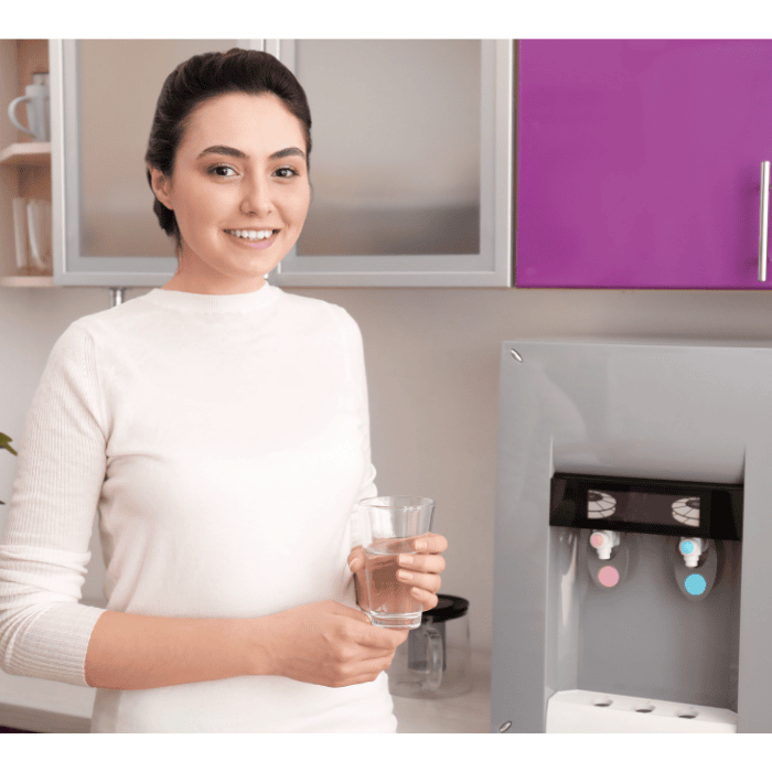 A woman with a glass of water and countertop dispenser