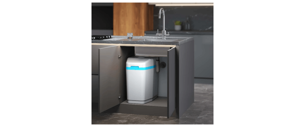 Under-cabinet Home water softener system installed underneath  a kitchen sink in white