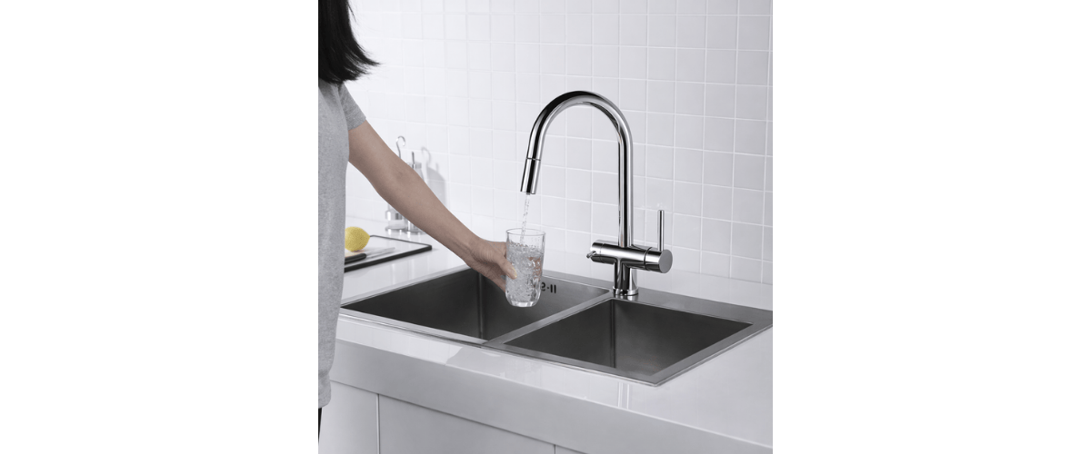 a chrome three way filter tap pouring water into a glass in a modern kitchen