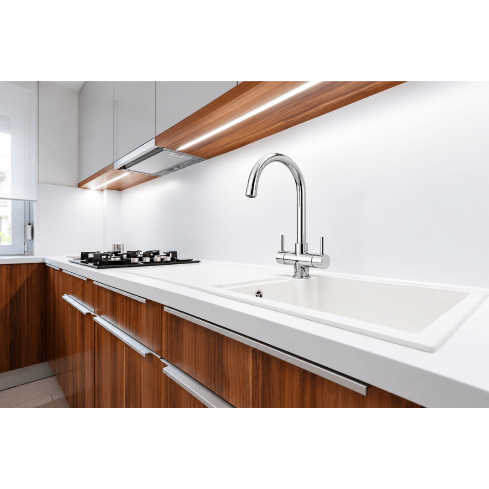 A modern kitchen sink setup featuring a goose neck chrome faucet mounted on a white countertop with a matching white basin, set against white cabinetry and wood-grain lower cabinets.