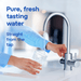 Person filling a glass with water from a modern kitchen faucet, with text about pure and fresh tasting water.