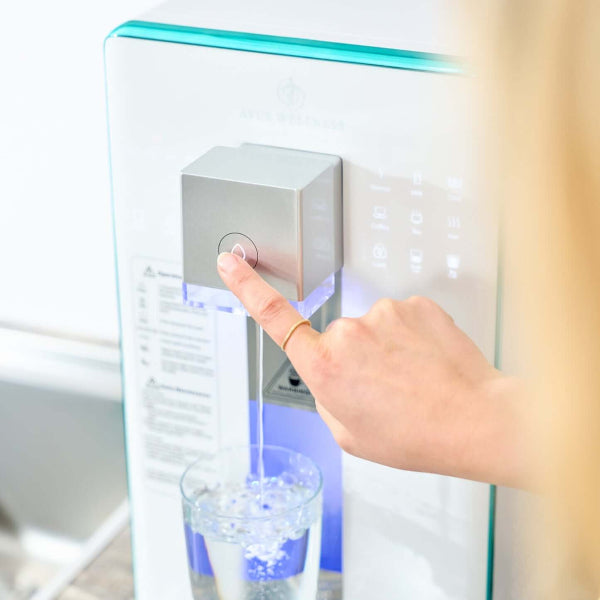 User pressing button to dispense water from the Ayus Wellness purifier