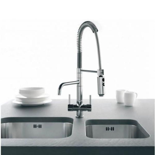 A chrome three way trilfow tap with pull out hose over a sink with cups and saucers