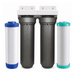 A whole house water filter kit with two dark gray cylindrical filter housings in the center and two replacement filter cartridges, one white with blue accents and one white with teal accents, shown on a plain white background.