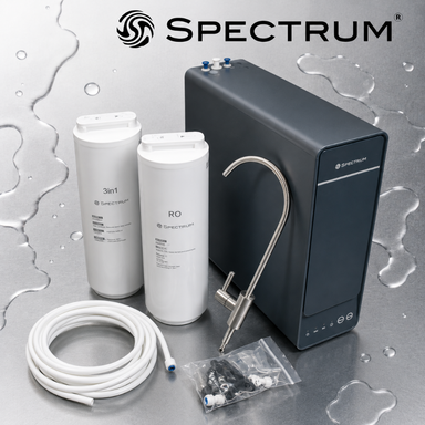 Spectrum RO water system kit on a metallic grey background with water droplets. The set includes a dark gray main device, two white filter cartridges, a coiled white hose, a curved metal faucet adapter, and small black filter parts in a clear bag.